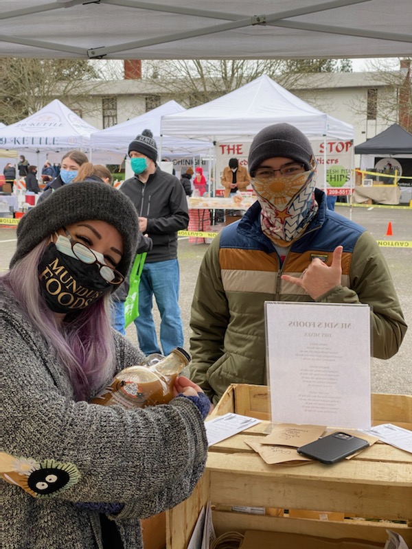 Ruby Madraine of Mundus Foods with a community member at a Portland farmers market