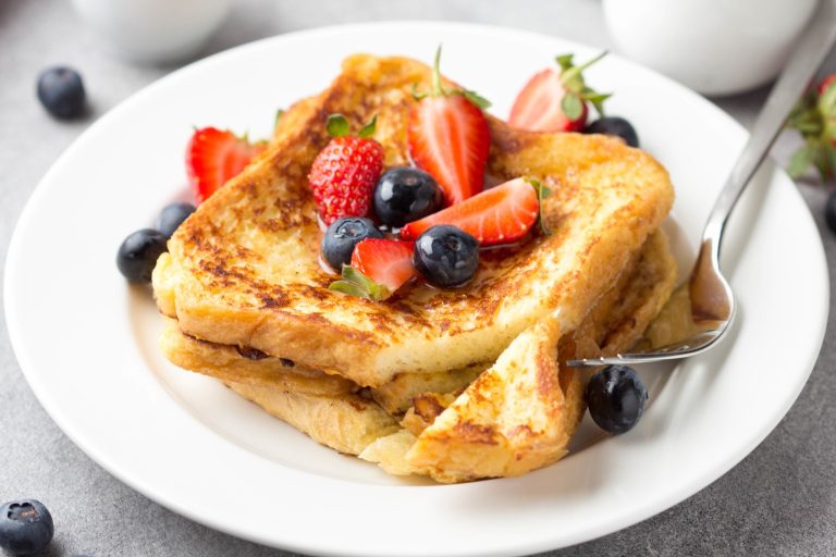 French toast topped with strawberries and blueberries on a white plate.