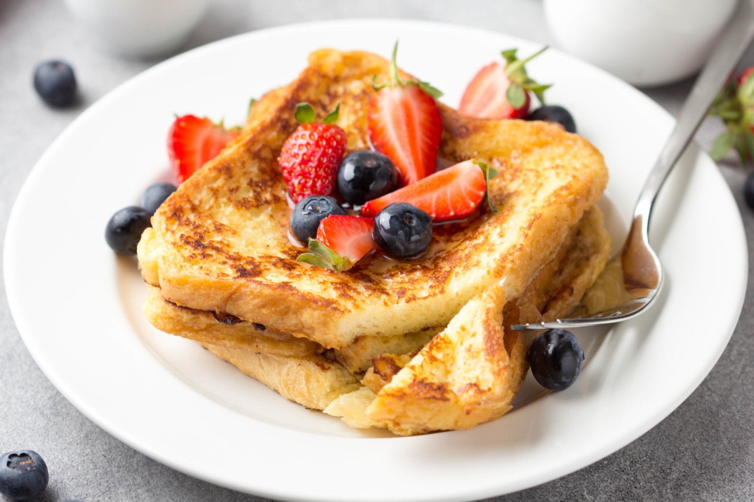 French toast topped with strawberries and blueberries on a white plate.