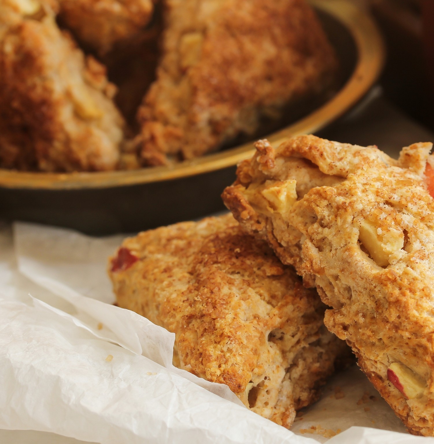 Golden scones with fruit pieces on parchment paper.